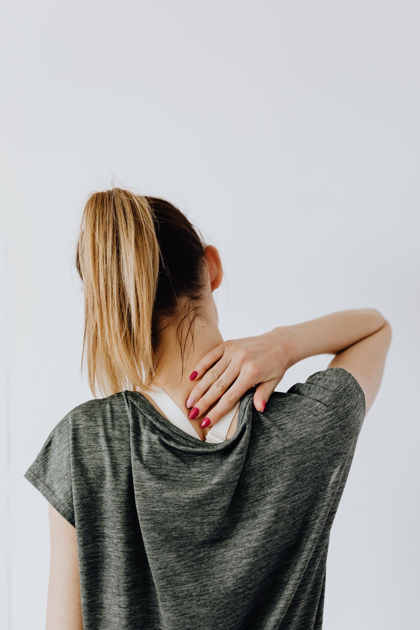 Person holding the back of their neck, illustrating chronic pain evaluation